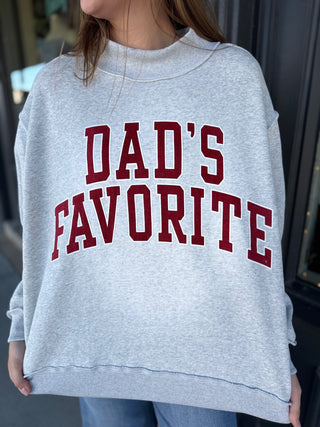 Gray sweatshirt with 'DAD'S FAVORITE' text in red worn by a person.