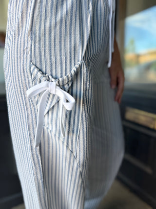 Blue and white striped apron with a tie, worn by a person in an indoor setting.