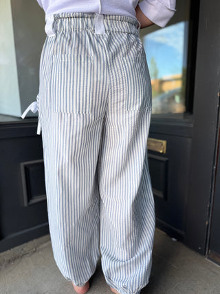 Person wearing blue and white striped pants standing in front of a door.