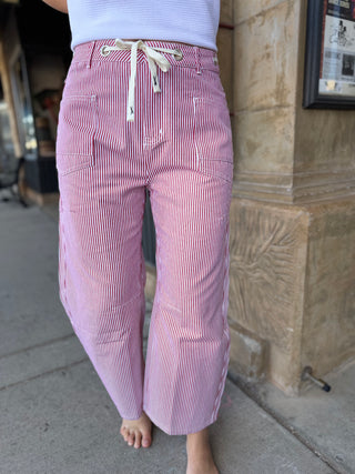Person wearing pink and white striped pants standing on a sidewalk.