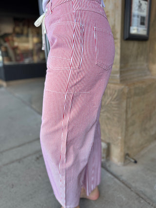 Red and white striped pants being worn, with a blurred background of a store interior.