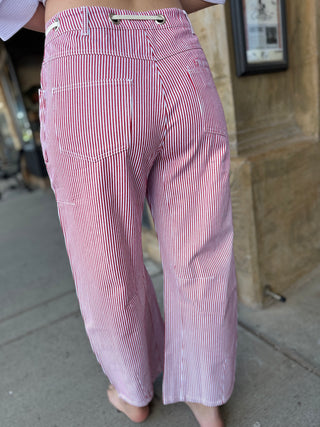 Red and white striped pants worn by a person on a sidewalk.