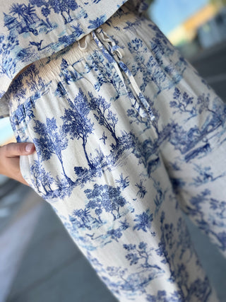 White hoodie with blue tree pattern worn by a person, blurred background
