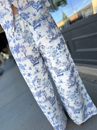 White pants with blue floral pattern on a blurred outdoor background