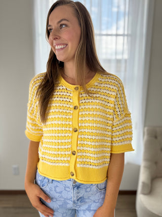 Woman wearing a yellow and white striped cardigan indoors