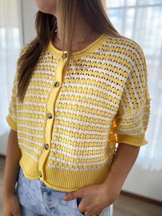 Person wearing a yellow and white striped cardigan with a blurred background
