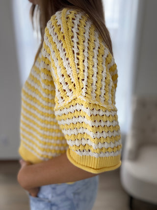 Person wearing a yellow and white patterned sweater indoors