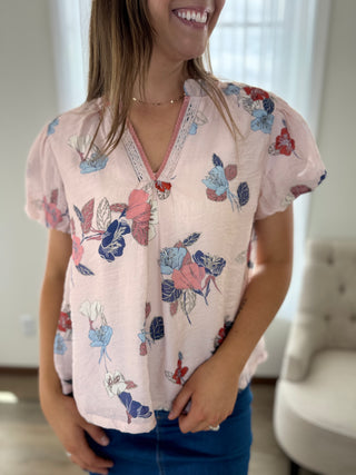 Woman wearing a pink floral blouse in an indoor setting
