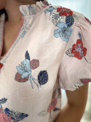 Close-up of a floral-patterned shirt with red, blue, and pink flowers on a light background.