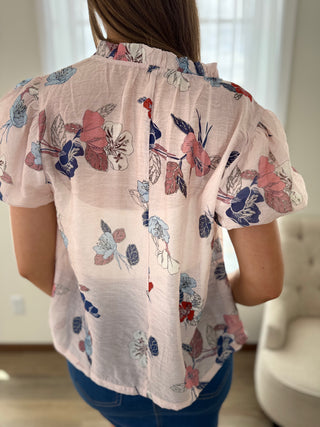Person wearing a floral blouse with a neutral background