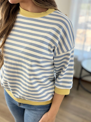 Lady standing wearing a stripe  knit top with banded sleeves and bottom.