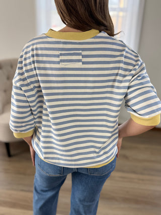 Lady standing wearing a stripe  knit top with banded sleeves and bottom.