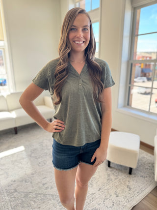 A photo of a girl in a green top posing in front of a white background.