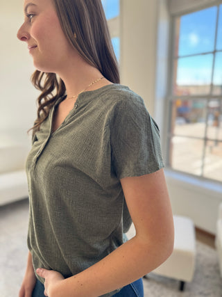 A photo of a girl in a green top posing in front of a white background.