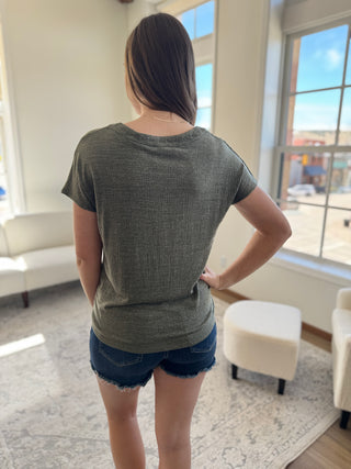 A photo of a girl in a green top posing in front of a white background.