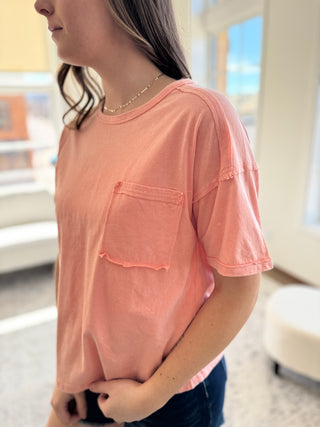 Lady standing wearing peach washed tee with front pocket and denim shorts.