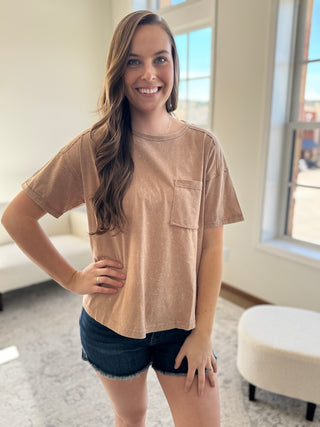 Lady standing wearing peach washed tee with front pocket and denim shorts.
