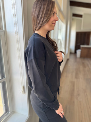 A person standing by a window wearing black sweatshirt.