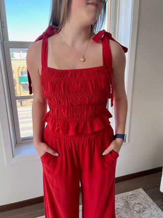 A person wearing a red smocked tank top with tie straps, paired with matching red pants.