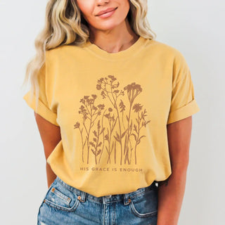 Person wearing a mustard yellow t-shirt with floral design and text on a plain background