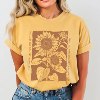 Person wearing a yellow t-shirt with sunflower design and text.