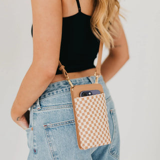 Person wearing a checkered phone pouch on a plain background