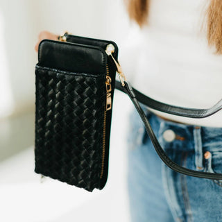 Black quilted phone pouch held by a person wearing a white shirt and blue jeans.